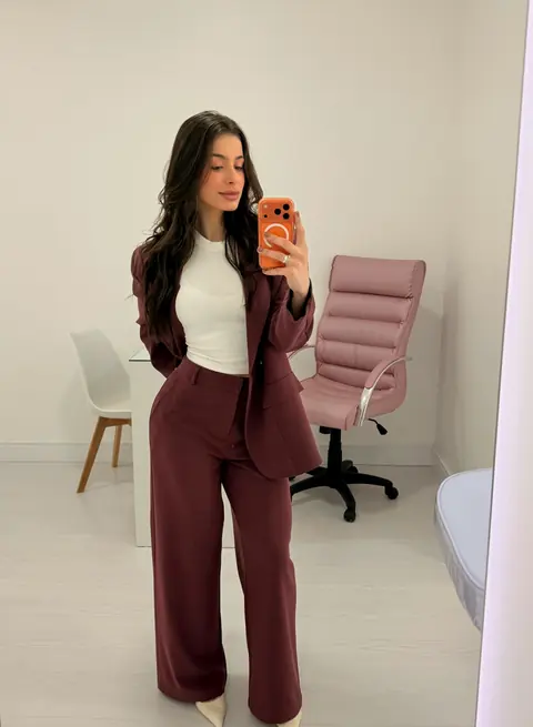 Tainá Cardoso na clínica, de terninho vinho, perto da cadeira rosa